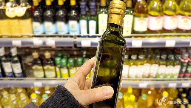 마트 진열대에서 올리브오일을 손에 들어 살펴보는 모습이다. / LADO-shutterstock.com