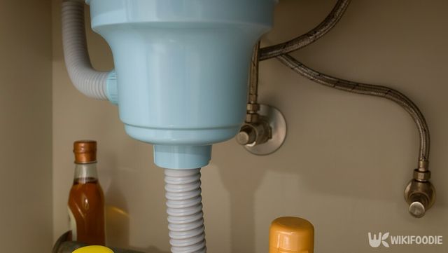싱크대 하부 장 배수관과 연결 호스, 주변 용기가 함께 보이는 구조다. / 위키푸디