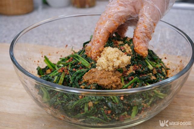 데친 시금치에 양념 재료들을 넣고 무치고 있다. / 위키푸디