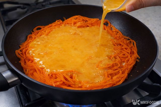 볶은 당근에 달걀물을 넣고 있다. / 위키푸디