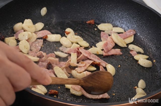 마늘과 베이컨을 팬에 굽고 있다. / 위키푸디