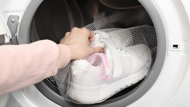 운동화를 세탁기에 넣고 있다. / New Africa-shutterstock.com