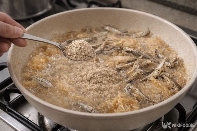 묵은지와 멸치를 조리고 있을 때 들깨가루를 넣고 있다. / 위키푸디