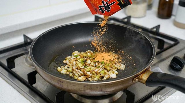 볶은 파와 마늘 위에 라면스프를 넣는 모습. / 위키푸디