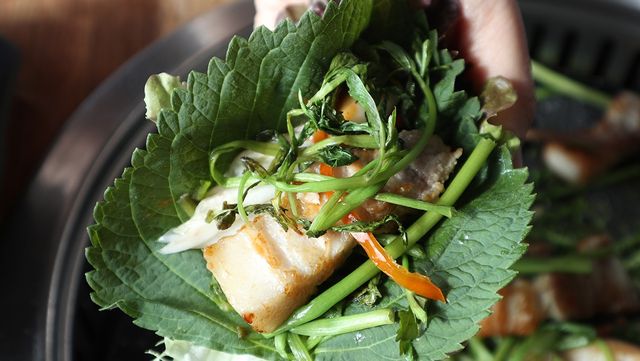 삼겹살에 깻잎을 싸 먹고 있다. / MIN and JJ-shutterstock.com
