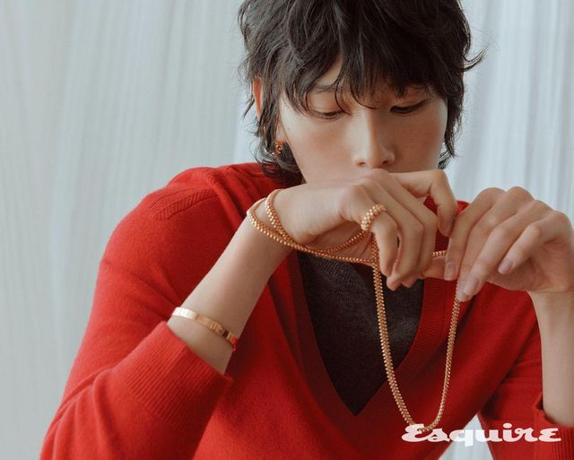 핑크 골드 클래쉬 드 까르띠에 싱글 라지 이어링, 오른손에 착용한 핑크 골드 LOVE 브레이슬릿, 핑크 골드 스몰 클래쉬 드 까르띠에 롱 네크리스, 소지에 낀 핑크 골드 클래쉬 드 까르띠에 미디엄 링. 스웨터 렉토.