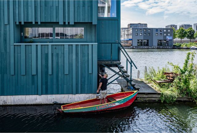 암스테르담 북쪽에 있는 수상마을 스혼스힙에서 한 남성이 자신의 집에 페인트로 칠하고 있다.