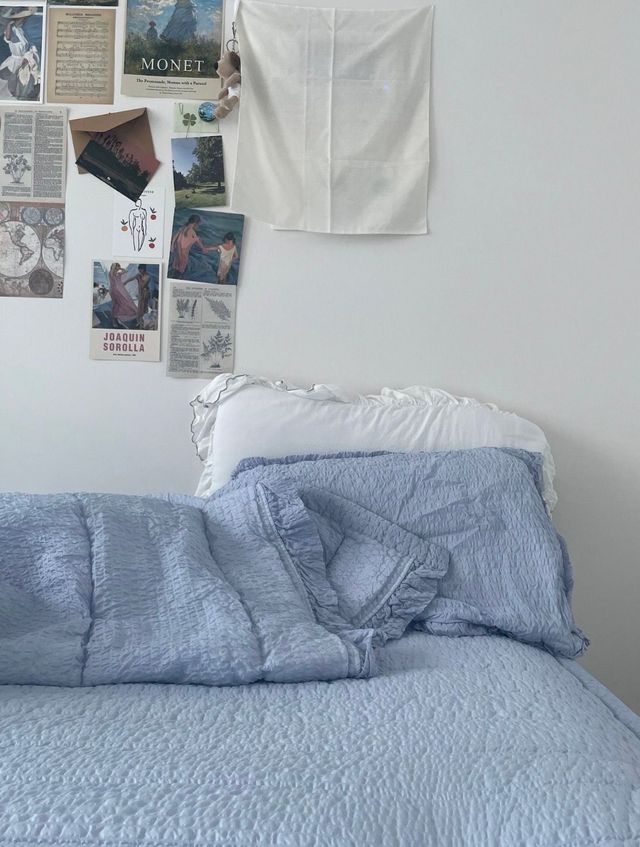 아이보리 바탕에 푸른 침구가 깔린 침대. 벽면에는 모네의 포스터와 엽서, 강아지 키링이 보인다. / 이미지 출처: 필자 촬영