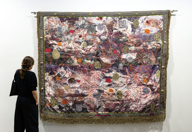 시안 다이릿(Cian Dayrit), 에코스(Echoes) 섹터 전시 전경, 아트 바젤 홍콩 2026. 필리핀의 지형도 위에 텍스트·아카이브 이미지·원주민 신화의 상징들을 중첩시킨 직조 작품. 작가는 이를 '대항 카토그래피(counter-cartography)'라 부른다. © Courtesy of Art Basel 