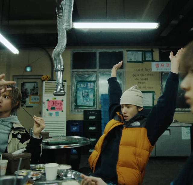 노스페이스 ‘눕시 700 조끼 패딩’ 오렌지 컬러를 입은 성현 / 이미지 출처: 코르티스 ‘REDRED’ 뮤직비디오