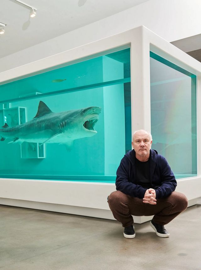  포름 알데히드에 갖힌 상어 앞에 앉아있는 데미안 허스트 / 이미지 출처: Damien Hirst photographed by Prudence Cuming Associates Ltd. © Damien Hirst and Science Ltd. All rights reserved, DACS/Artimage 2023