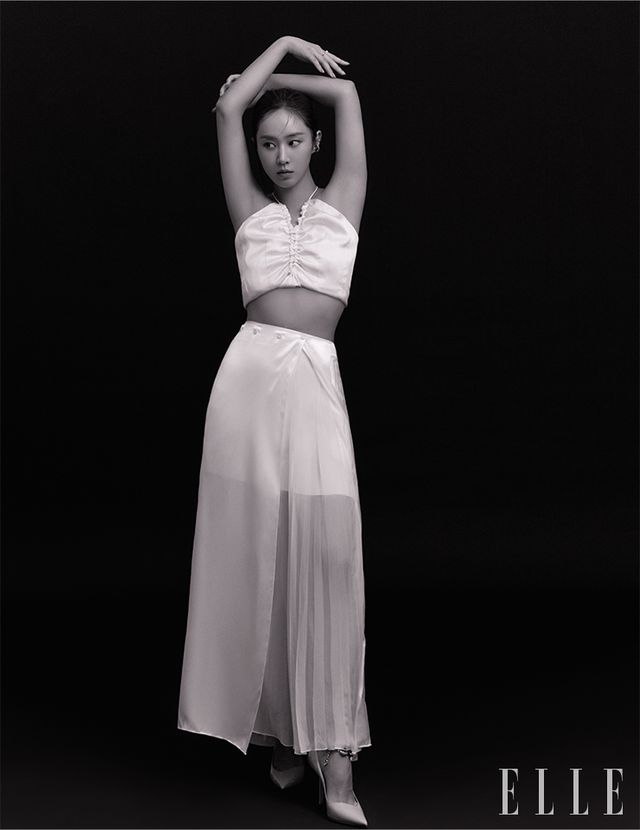 슬리브리스 톱은 LVIR. 스커트는 Ports 1961. 슈즈는 Jimmy Choo. 귀 아래쪽 이어 커프는 Sentiments. 귓바퀴 이어 커프는 The Part Of. 오른손 중지 링은 Engbrox. 검지링은 Le Haul. 