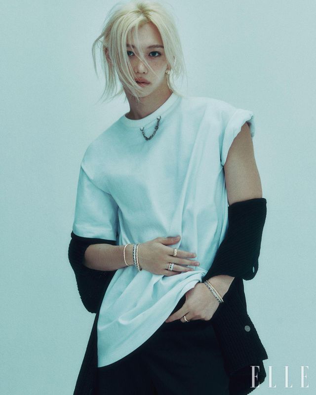 다이아몬드 세팅 르 다미에 드 루이 비통 후프 이어링과 오른손에 레이어드한 옐로골드 르 다미에 드 루이 비통 브레이슬릿, 화이트골드 르 다미에 드 루이 비통 라지 브레이슬릿, 검지에 착용한 옐로골드 르 다미에 드 루이 비통 더블 링, 약지에 착용한 화이트골드 르 다미에 드 루이 비통 라지 링, 옐로골드 르 다미에 드 루이 비통 링, 왼손에 착용한 옐로골드 르 다미에 드 루이 비통 라지 브레이슬릿, 화이트골드 르 다미에 드 루이 비통 라지 브레이슬릿, 중지에 착용한 옐로골드 르 다미에 드 루이 비통 라지 링, 쇼트 슬리브 카디건, 체인 디테일의 티셔츠, 블랙 울 팬츠는 모두 Louis Vuitton.