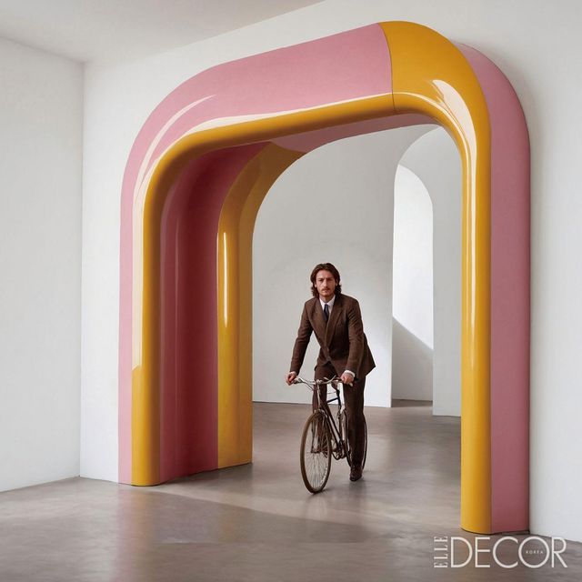 생동감 넘치는 아치 아래 수트를 차려입고 자전거를 타고 있는 패디 파이크의 모습에서 위트가 느껴진다.