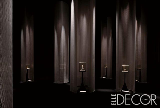 어두운 동굴 속 ‘라’ 직물을 사용해 빛이 하늘에서 흘러내리는 듯한 장면을 연출한 전시의 도입 프롤로그 . 그 아래는 미스터리 클락과 프리즘 클락이 전시되어 있다. 