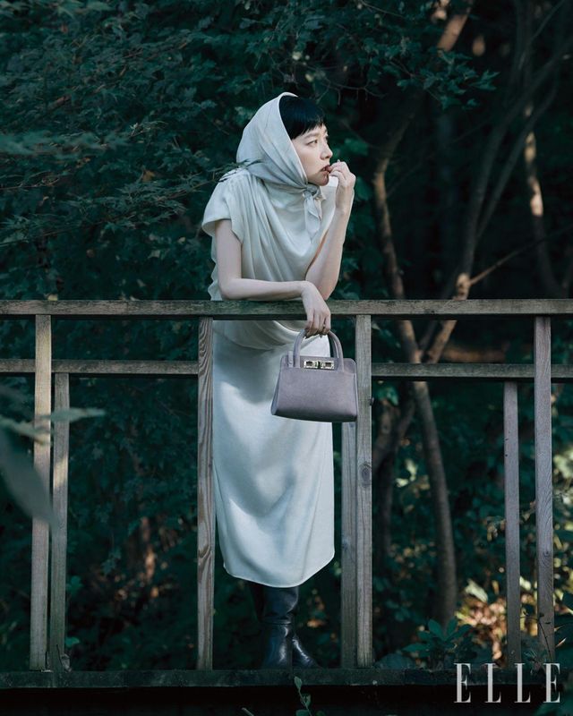 화이트 새틴 슬리브리스 드레스와 머리에 두른 스카프, 스웨이드 미니 토트백, 나파 레더 하이힐 부츠는 모두 Fabiana Filippi.