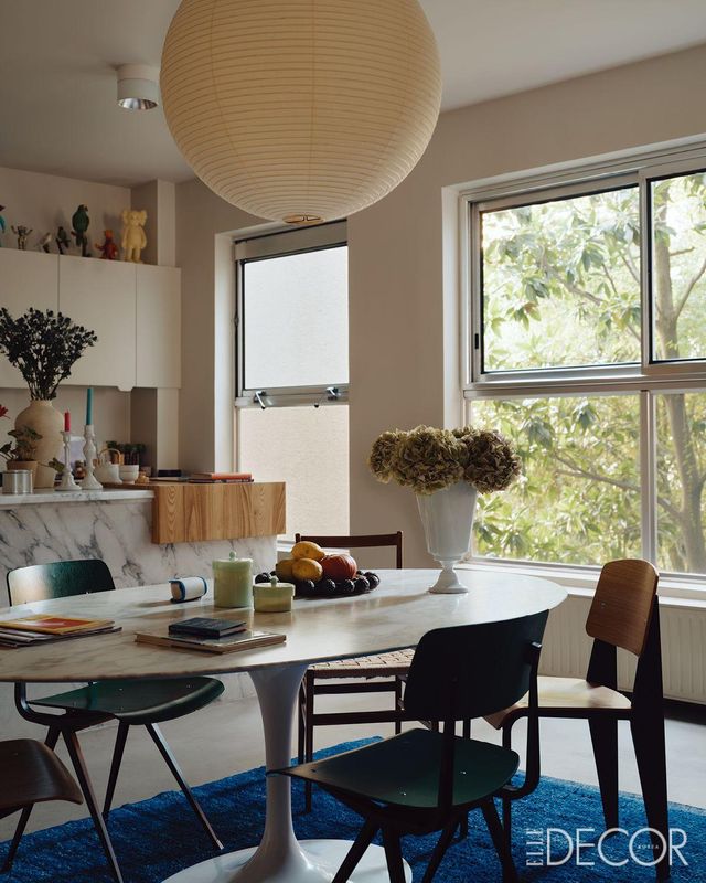  대리석으로 만든 아일랜드와 테이블, 커다란 조명이 따듯한 분위기를 연출하는 거실 부엌 캐비닛 위에는 잔이 수집하는 빈티지 장난감 컬렉션을 발견할 수 있다. 테이블은 놀(Knoll). 라이팅은 이사무 노거치(Isamu Noguchi). 의자는 장 프루베(Jean Prouve)의 디자인. 