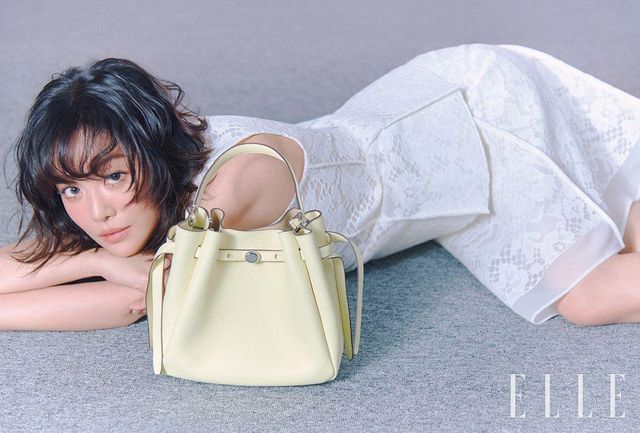차주영이 착용한 트리밍 디테일의 레이스 톱과 스커트, 레몬 컬러 로미 페블드 버킷 백은 모두 Tory Burch.