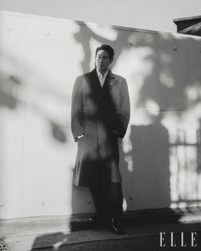 그레이 롱 코트는 Maison Margiela. 화이트 셔츠와 블랙 팬츠는 모두 Dolce & Gabbana. 로퍼는 Christian Louboutin. 