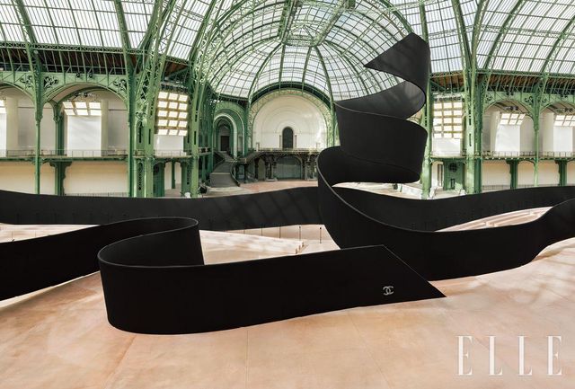 블랙 리본 형태의 대형 설치물이 공간을 감싸듯 자리한 환상적인 무대에서 펼쳐진 2025~2026 F/W 샤넬 레디 투 웨어 컬렉션은 크기와 길이, 비율의 변주 속에서 시적 감성을 풀어냈다. 