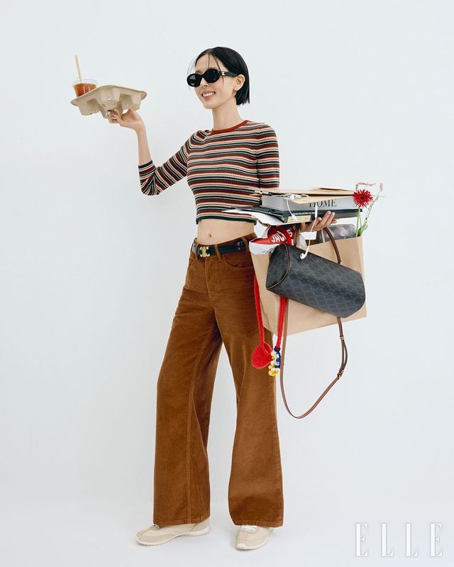 탠 트리옹프 캔버스 & 카프스킨 실린더 백, 페어 아일 캐시미어 크루넥 스웨터, 코듀로이 졸린 진, 셀린느의 첫 벨트 커스텀 및 리버서블 컬렉션인 '라 부클(LA BOUCLE)'의 탈부착 가능한 트리옹프 골드 메탈 버클과 블랙 레더 & 트리옹프 캔버스의 리버서블 스트랩, 레드 컬러 캐시미어 니트 파우치, 트리옹프 01 아세테이트 선글라스, 레이서 로우 탑 트리옹프 스니커즈는 모두 Celine.