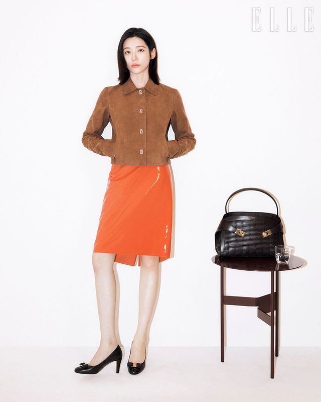 아티저널 크래프츠맨십을 구현한 위빙 허그 백, 아이코닉한 간치니 버클 장식의 스웨이드 재킷, 페이던트 오렌지 컬러 스커트, 보 장식의 바라 펌프스는 Ferragamo.