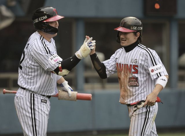 LG 김현수(왼쪽)가 26일 잠실구장에서 열린 한화와 KS 1차전 도중 득점을 올린 신민재와 손뼉을 마주치고 있다. 잠실｜뉴시스