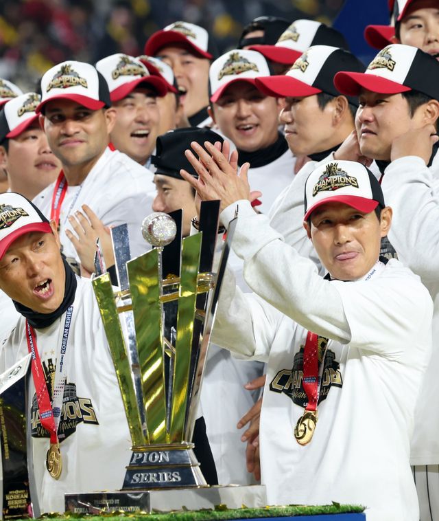 LG 염경엽 감독(오른쪽 앞)이 31일 대전한화생명볼파크에서 열린 ‘2025 신한 SOL 뱅크 KBO PS’ 한화와 한국시리즈 5차전에서 4-1로 이겨 통합우승을 확정한 뒤 트로피 옆에서 박수를 치고 있다. 대전｜뉴시스