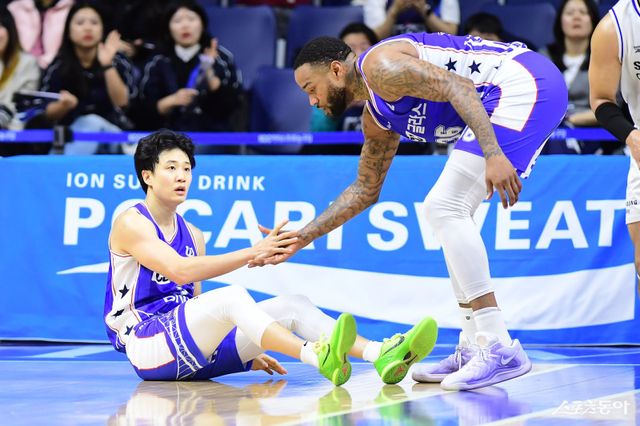 KCC 허웅(왼쪽)이 24일 부산 사직체육관에서 열린 ‘2025~2026 LG전자 프로농구’ 정규리그 3라운드 삼성과 홈경기서 숀 롱의 손을 잡고 일어나려 하고 있다. 허웅은 이날 경기 도중 발에 통증을 느껴 후반전을 뛰지 못했다. 사진제공｜KBL