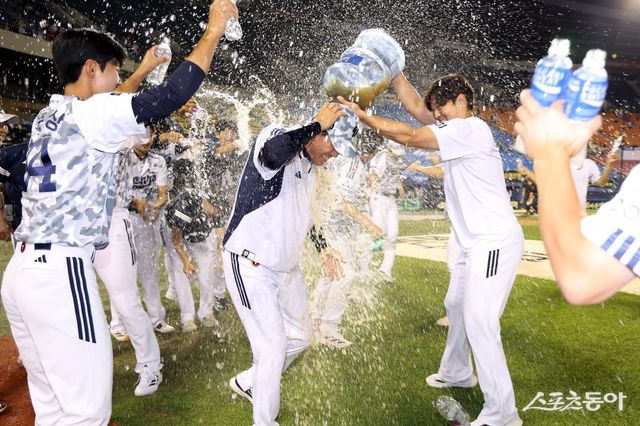 &nbsp;조성환 두산 감독대행(가운데)은 5일 잠실 KIA전에서 연장 10회말 2-1 승리를 이끌었다. 경기 뒤 선수단에게 첫 승 기념 물세례를 맞고 있다. 사진제공｜두산 베어스