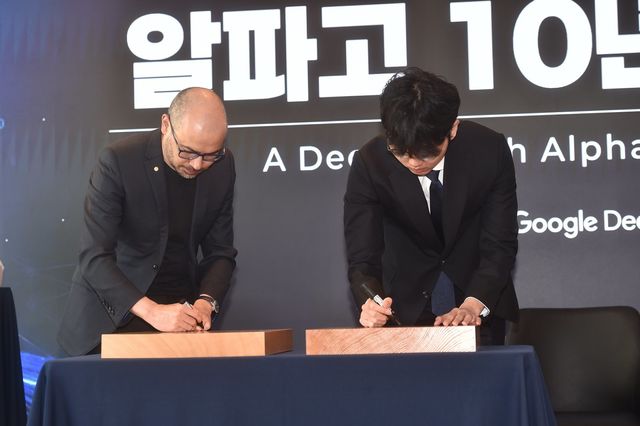 대국 후 바둑판에 사인을 하고 있는 데미스 허사비스 CEO(왼쪽)와 신진서 9단 사진제공 ｜한국기원