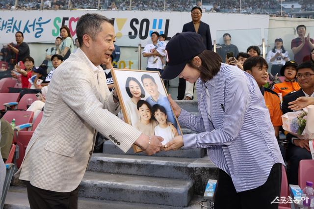 박정원 두산그룹 회장이 지난해 ‘소방가족의 날’ 행사서 순직 소방관 유가족에게 AI로 복원된 가족 사진을 전달하고 있다. 사진제공｜두산 베어스
