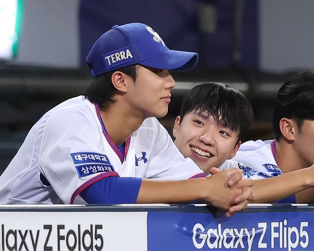 삼성 라이온즈 내야수 이재현(왼쪽)과 외야수 김현준이 2023 KBO리그 정규시즌 경기 중 더그아웃에서 선수들의 플레이를 지켜보며 대화를 나누고 있다. 이재현과 김현준은 팀 동료 김지찬과 함께 '굴비즈'로 불린다. 삼성 라이온즈 제공