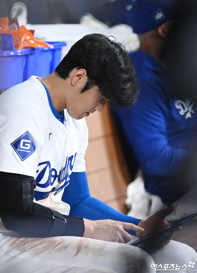 미국 메이저리그 LA 다저스의 슈퍼스타 오타니 쇼헤이가 지난달 21일 오후 서울 구로구 고척스카이돔에서 열린 2024 메이저리그 월드투어 서울시리즈 다저스와 샌디에이고 파드리스의 경기에서 더그아웃에 앉아 투수의 데이터를 확인하고 있다. 엑스포츠뉴스 DB