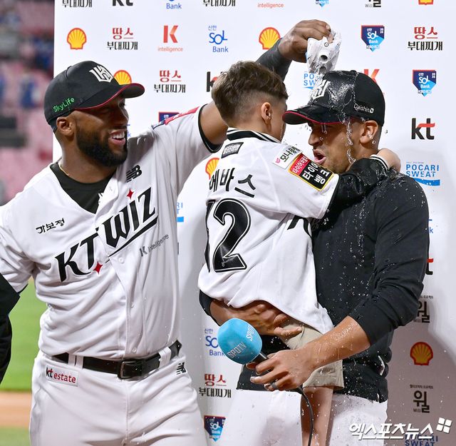 왼쪽에 선 KT 위즈 멜 로하스 주니어가 시즌 첫 승 후 인터뷰 중인 윌리엄 쿠에바스에게 물을 붓고 있다. 엑스포츠뉴스 수원, 김한준 기자
