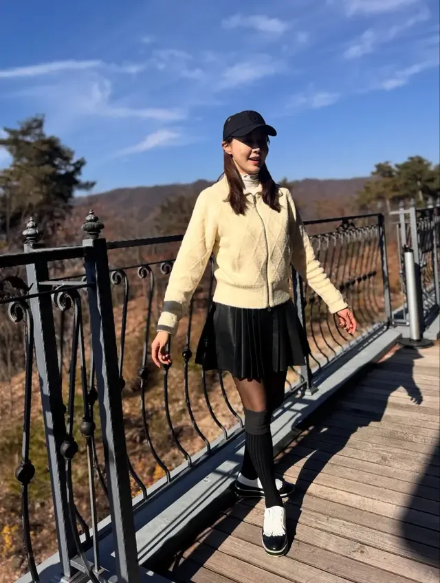 김민아가 맑은 초겨울 필드 위에서 크림 퍼 집업과 블랙 플리츠 스커트 조합의 라운드룩을 선보이며 포즈를 취하고 있다. /사진=김민아 인스타그램