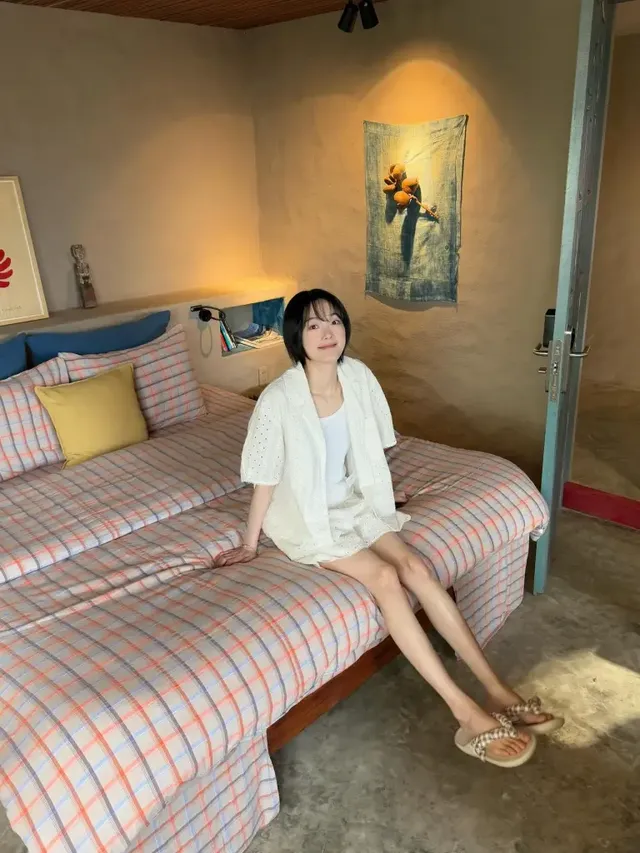 옅은 베이지 슬리브리스에 노란 체크 셔츠와 와이드 데님 팬츠를 매치하여 해변에서 여유로운 분위기를 즐기는 이유미. /사진=이유미 인스타그램