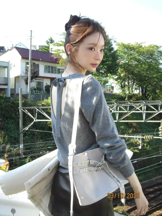  뒤에서 본 니트의 백리본 디테일과 크림빛 미니백이 어우러져 로맨틱한 분위기를 더한다. /사진=강민경 인스타그램