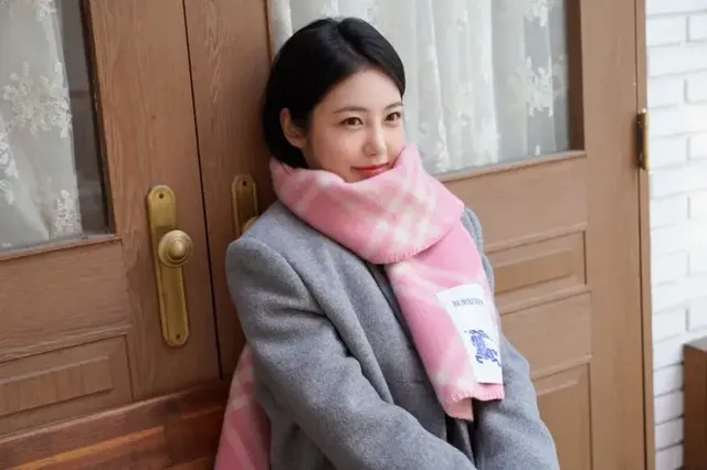 겨울 햇살 아래 나무 벤치에 앉아 포근한 핑크 체크 머플러를 두른 신예은의 모습. /사진=신예은 인스타그램