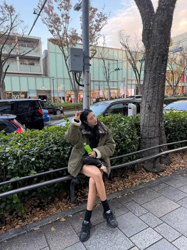  앉아 있는 포즈로 카키 점퍼의 포근한 질감과 블랙 미니 백, 그린 음료병 디테일을 보여주는 안근영. /사진=안근영 인스타그램