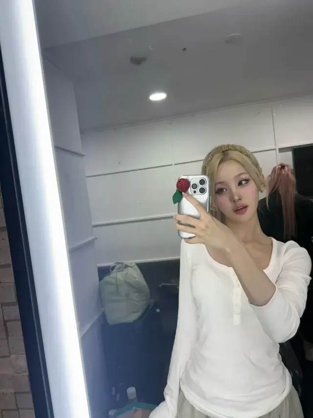 거울 앞에서 따스한 조명 아래 포즈를 취하고 있는 벨의 편안한 화이트 티셔츠 스타일. /사진=KISS OF LIFE 인스타그램