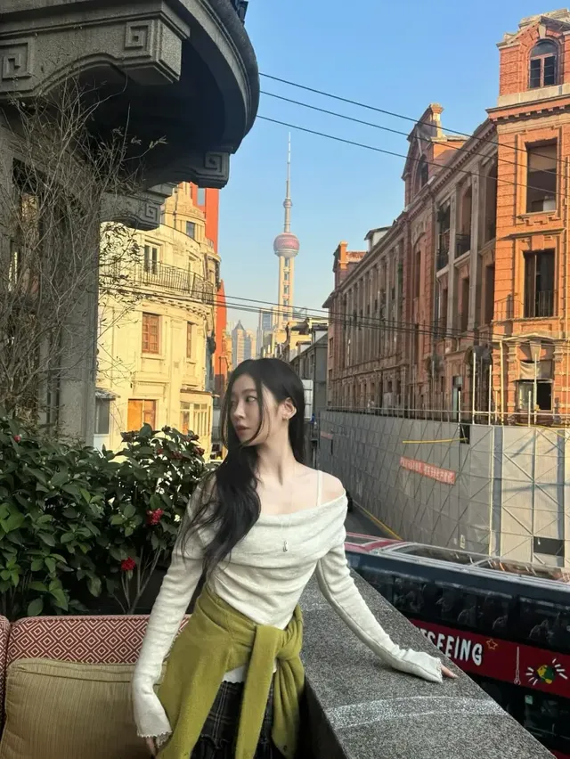 동방명주 타워를 배경으로 크림색 오프숄더 니트와 허리에 멘 올리브 니트로 도시적인 캐주얼룩을 선보였습니다. /사진=송지우 인스타그램