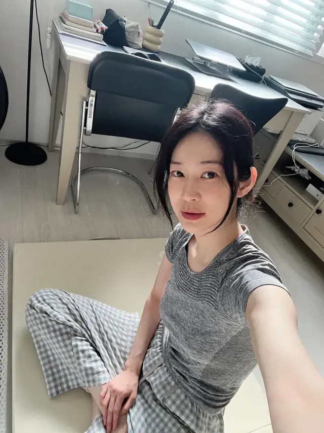 창가에 앉아 그레이 티셔츠와 체크 와이드 팬츠로 편안한 홈 무드를 선보이는 오혜원. /사진=오혜원 인스타그램