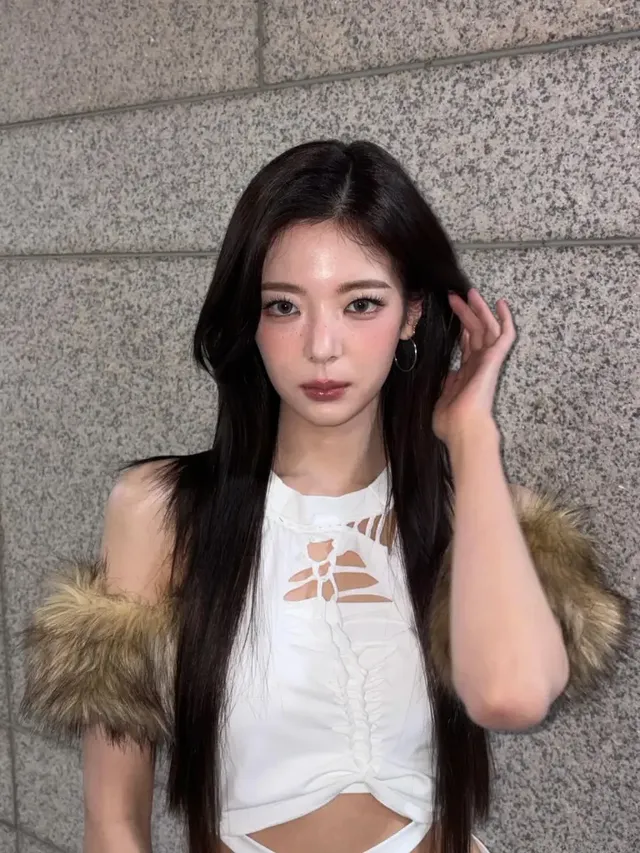 차가운 석재 벽을 배경으로 화이트 컷아웃 톱을 착용하고 포즈를 취한 리아의 모습. /사진=리아 인스타그램