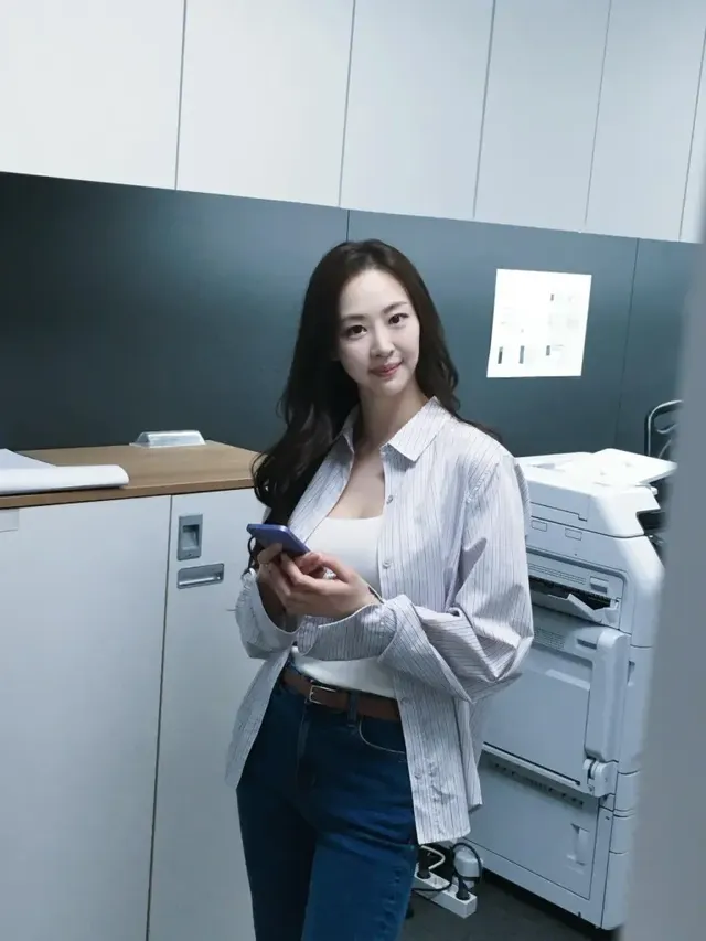 오피스 배경 속 다솜이 블루 스트라이프 셔츠와 데님 팬츠로 연출한 단정하면서도 세련된 캐주얼 룩. /사진=다솜 인스타그램