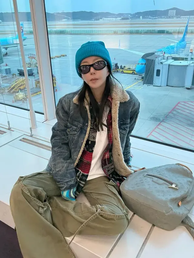 창가에 편안하게 앉아 창밖의 활주로를 배경으로 힙한 카고 팬츠 스타일링을 선보이는 슈. /사진=슈 인스타그램