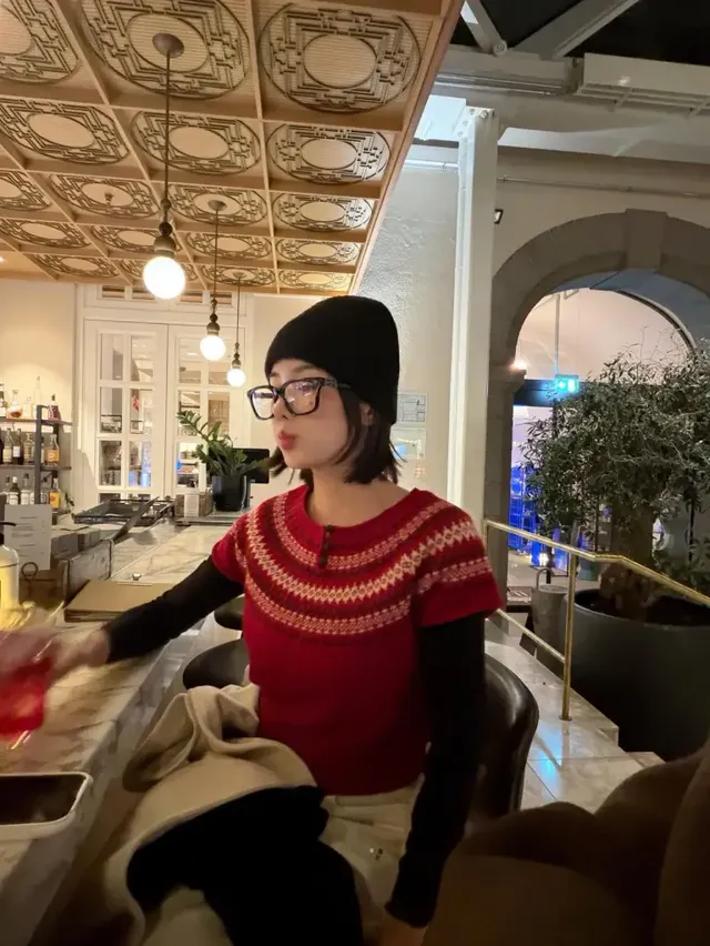 레드 페어아일 니트와 블랙 비니를 매치해 사랑스러운 홀리데이 무드를 완성한 권은비가 바 테이블에서 포즈를 취하고 있다. /사진=권은비 인스타그램