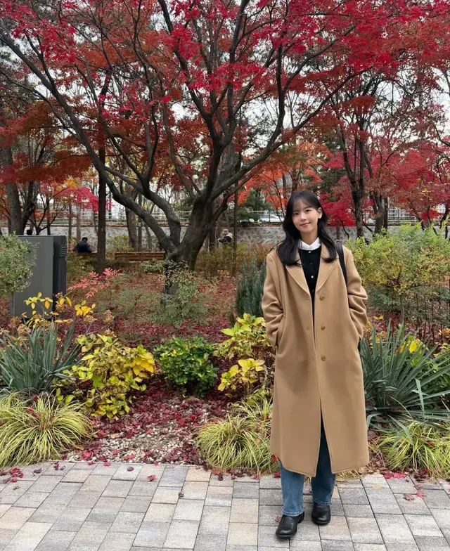 붉은 단풍 배경과 조화를 이루는 카멜 코트로 우아한 분위기를 완성한 배우 강한나의 정면 모습./사진=강한나 인스타그램