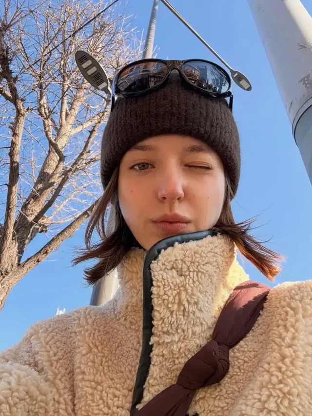 야외 조명 아래에서 시어링 재킷과 비니를 매치해 자유롭고 편안한 스트릿 감성을 뽐내는 모습./사진=안젤리나 다닐로바