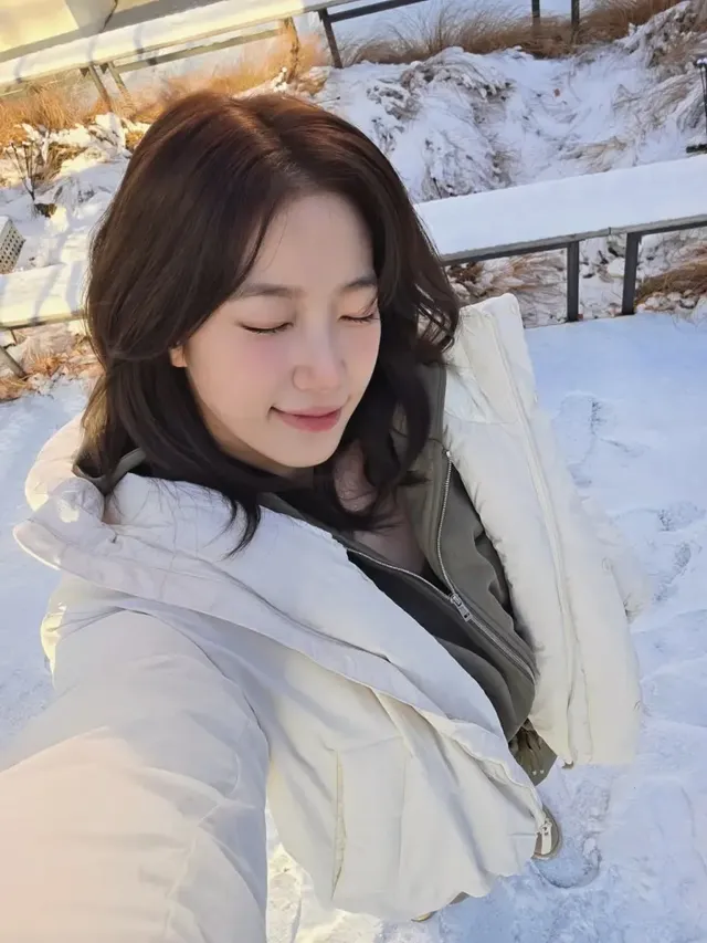 겨울 감성이 물씬 풍기는 설경을 배경으로, 카즈하가 편안하면서도 스타일리시한 윈터 패딩룩으로 시선을 사로잡는다. /사진=카즈하 인스타그램